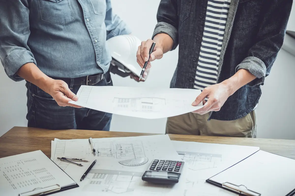 deux hommes qui discutent en regardant des plans de travaux