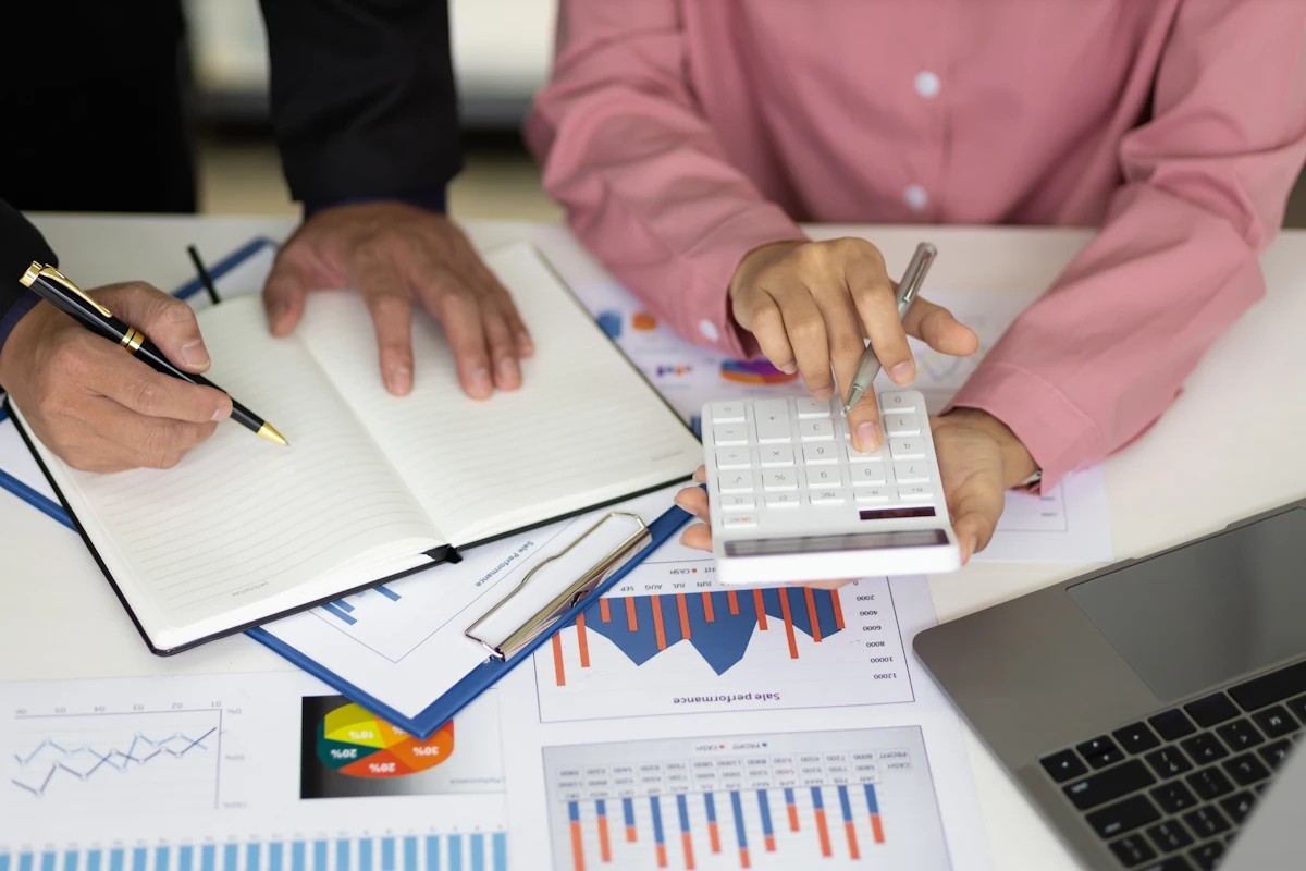des personnes qui font des calculs en regardant un bilan comptable